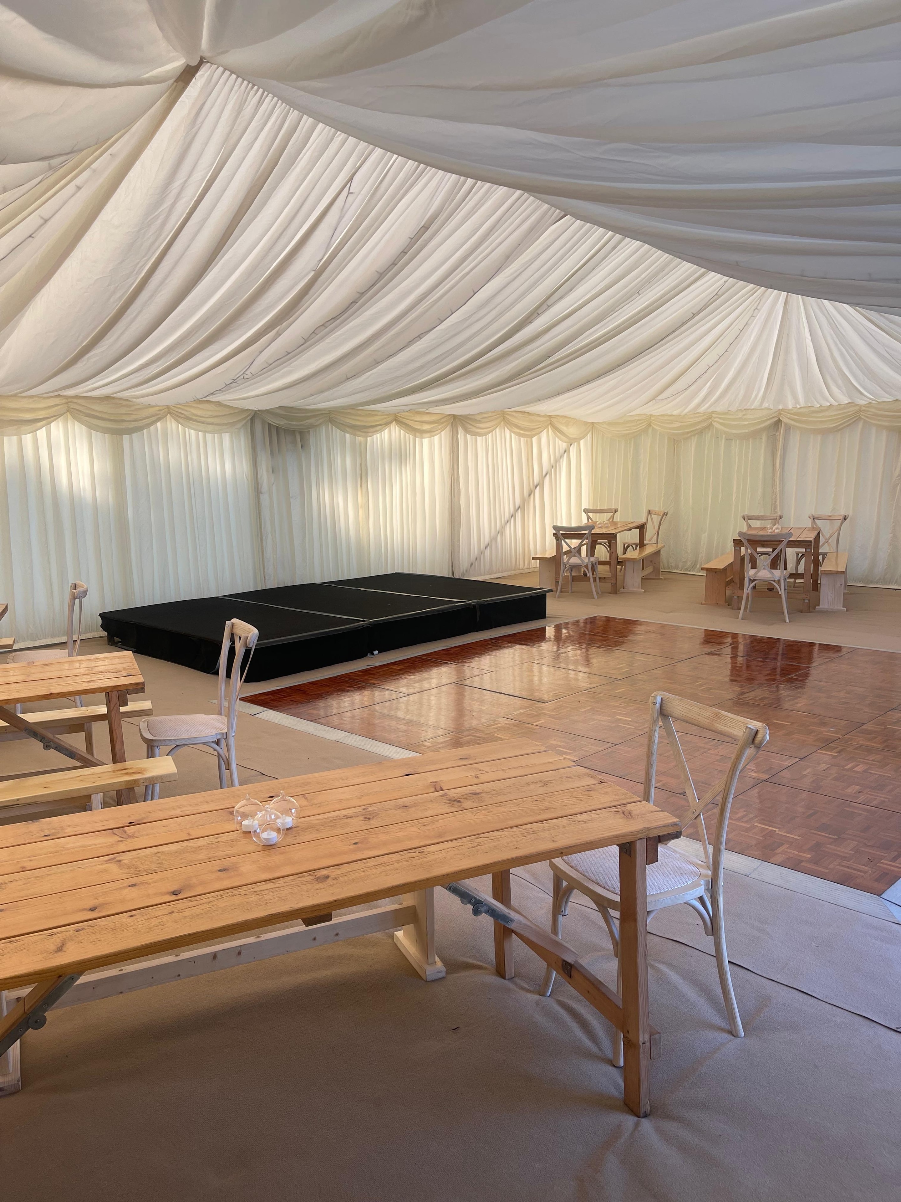 Marquee interior with parquet dance floor, staging, tables and chairs
